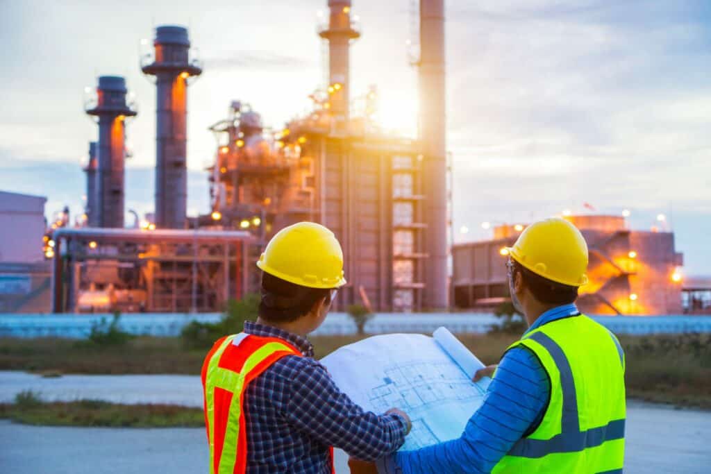 Two construction workers observe a site wearing PPE