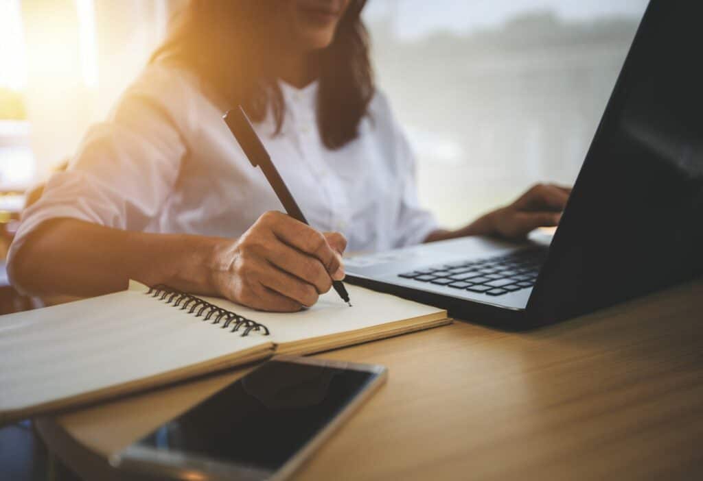 Writing notes beside a laptop