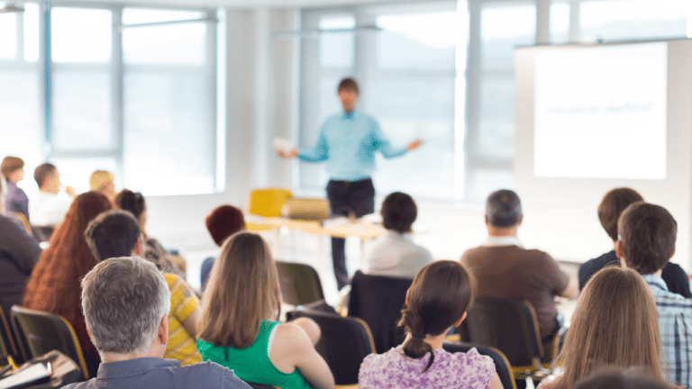 Learning culture depicted by a room of employees watching a speaking presentation