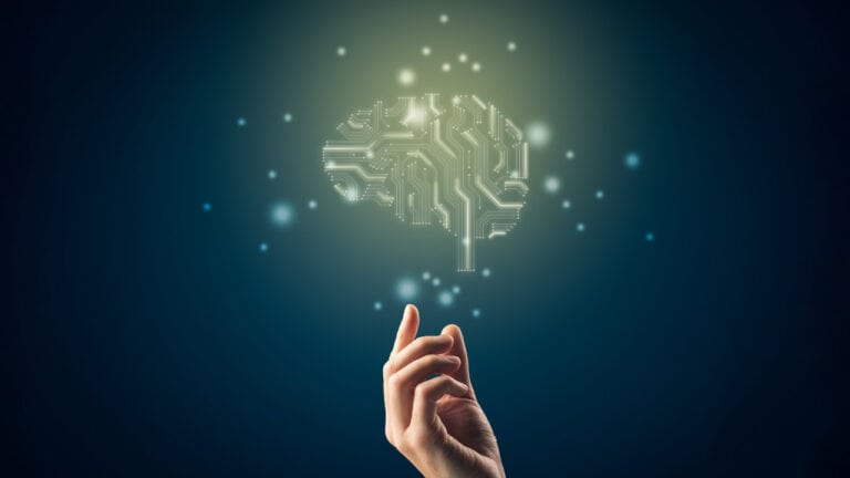 A hand reaching toward a glowing digital brain made of circuit patterns, symbolizing AI scoring in certification, set against a dark blue background with floating light particles.