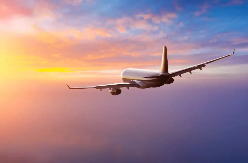 An Airplane flying in the sky as the sun sets over the clouds