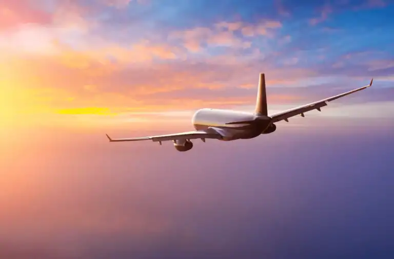 An Airplane flying in the sky as the sun sets over the clouds